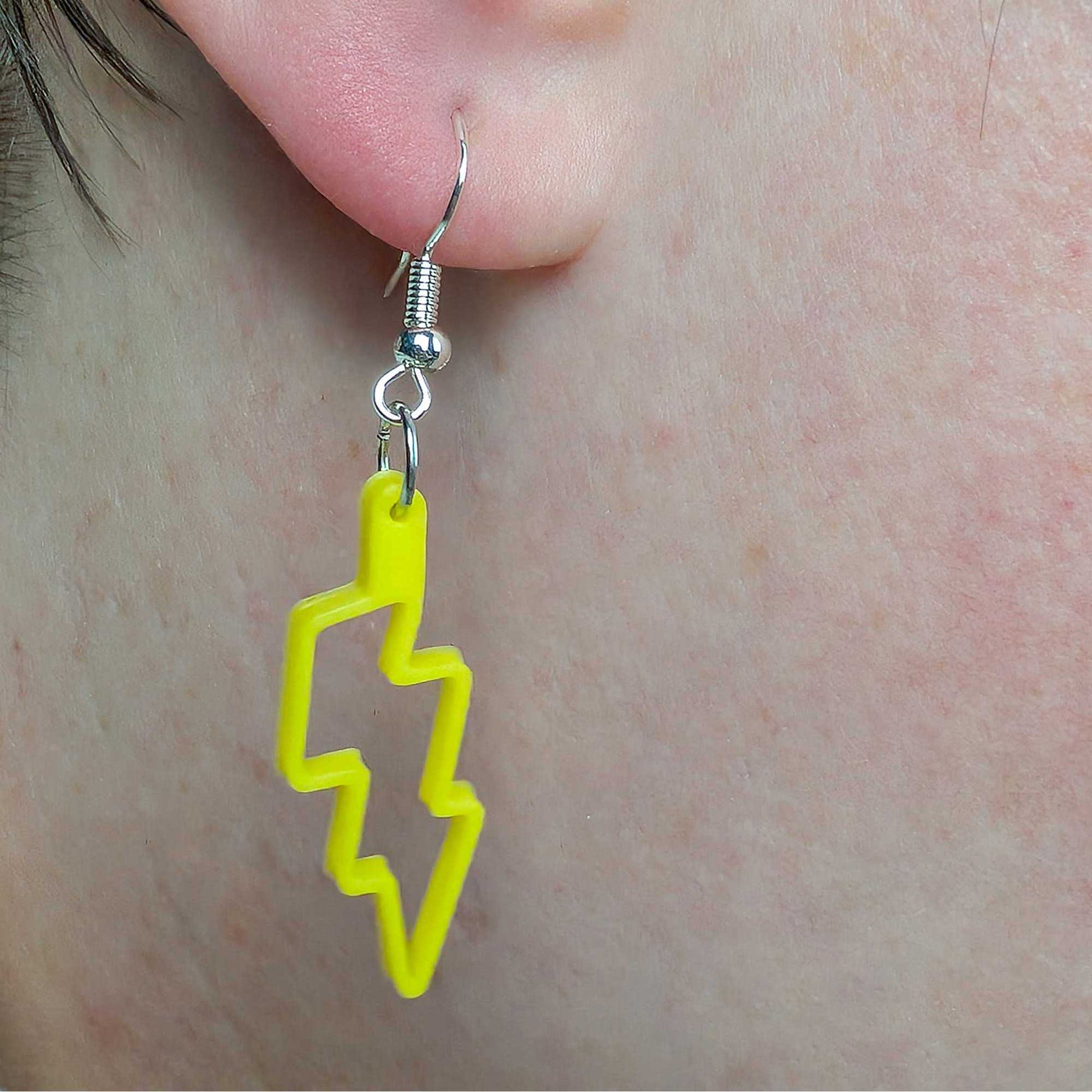 Yellow lightning bolt earring on a person's ear