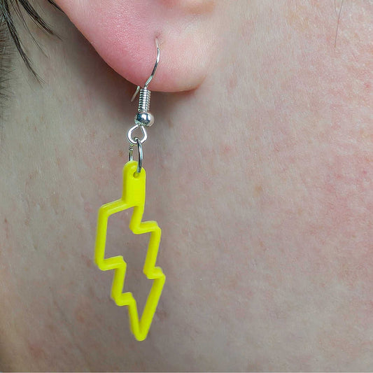 Yellow lightning bolt earring on a person's ear