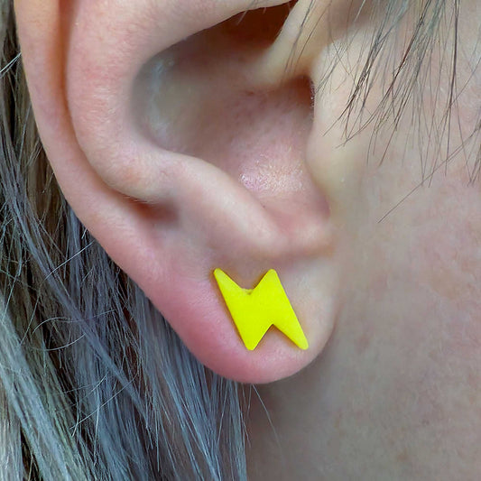 Close-up of an ear wearing a yellow lightning bolt earring.