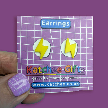Earring packaging with lightning bolt design held by a hand on a purple background