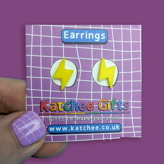 Earring packaging with lightning bolt design held by a hand on a purple background