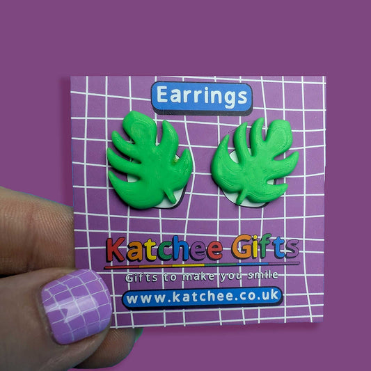 Green leaf-shaped earrings on a Katchee Gifts card with a purple background