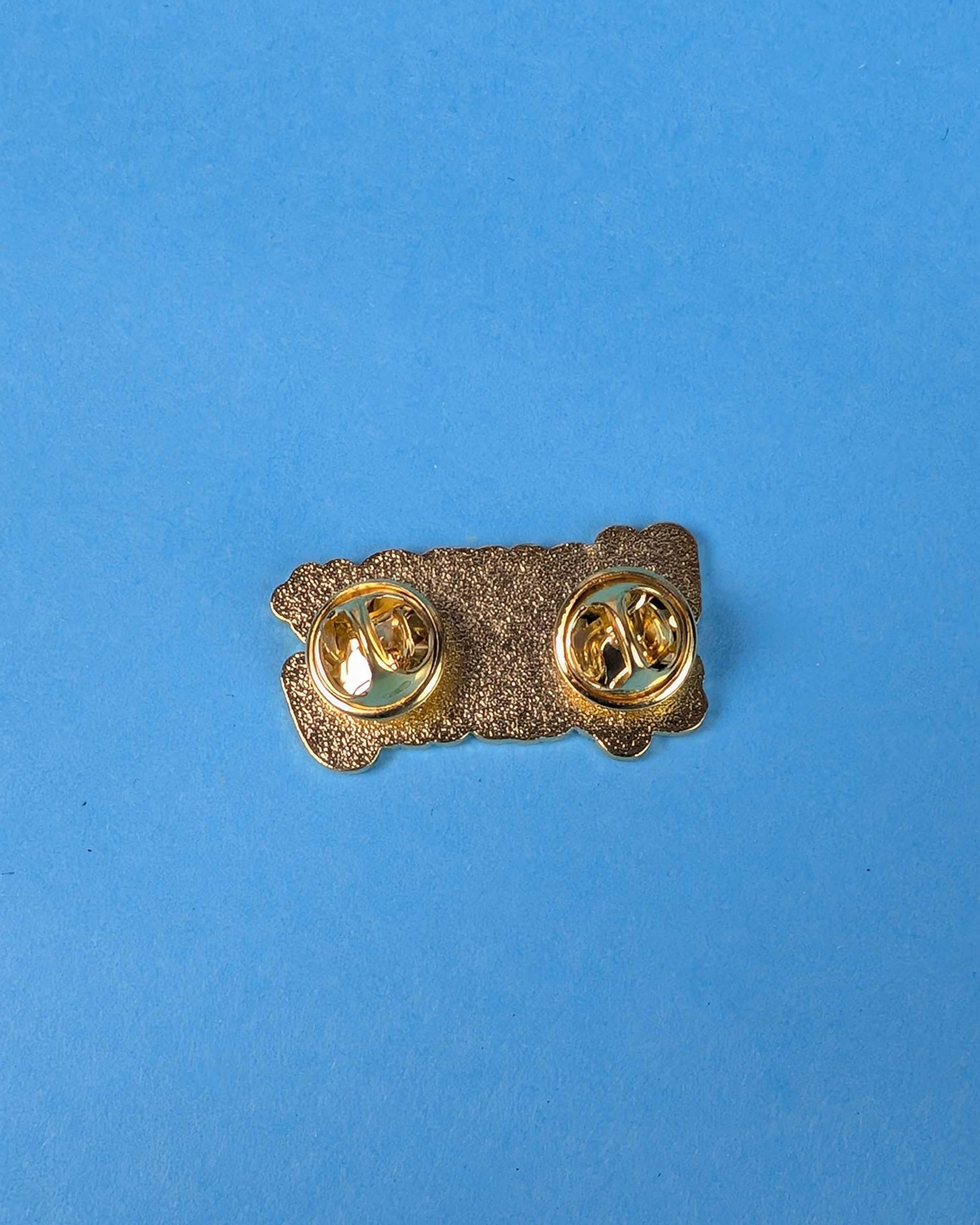 Gold-colored brooch on a blue background