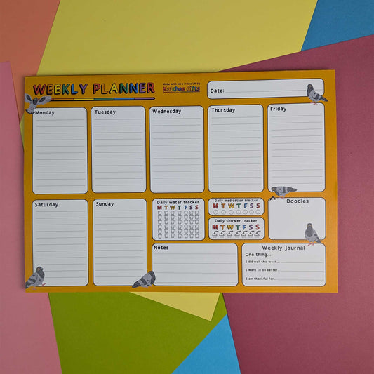 A weekly planner pad with a bright yellow-orange border and white lined sections for each day of the week, placed on a colorful geometric paper background.