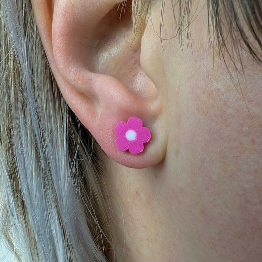 Close-up of an ear wearing a pink flower-shaped earring.