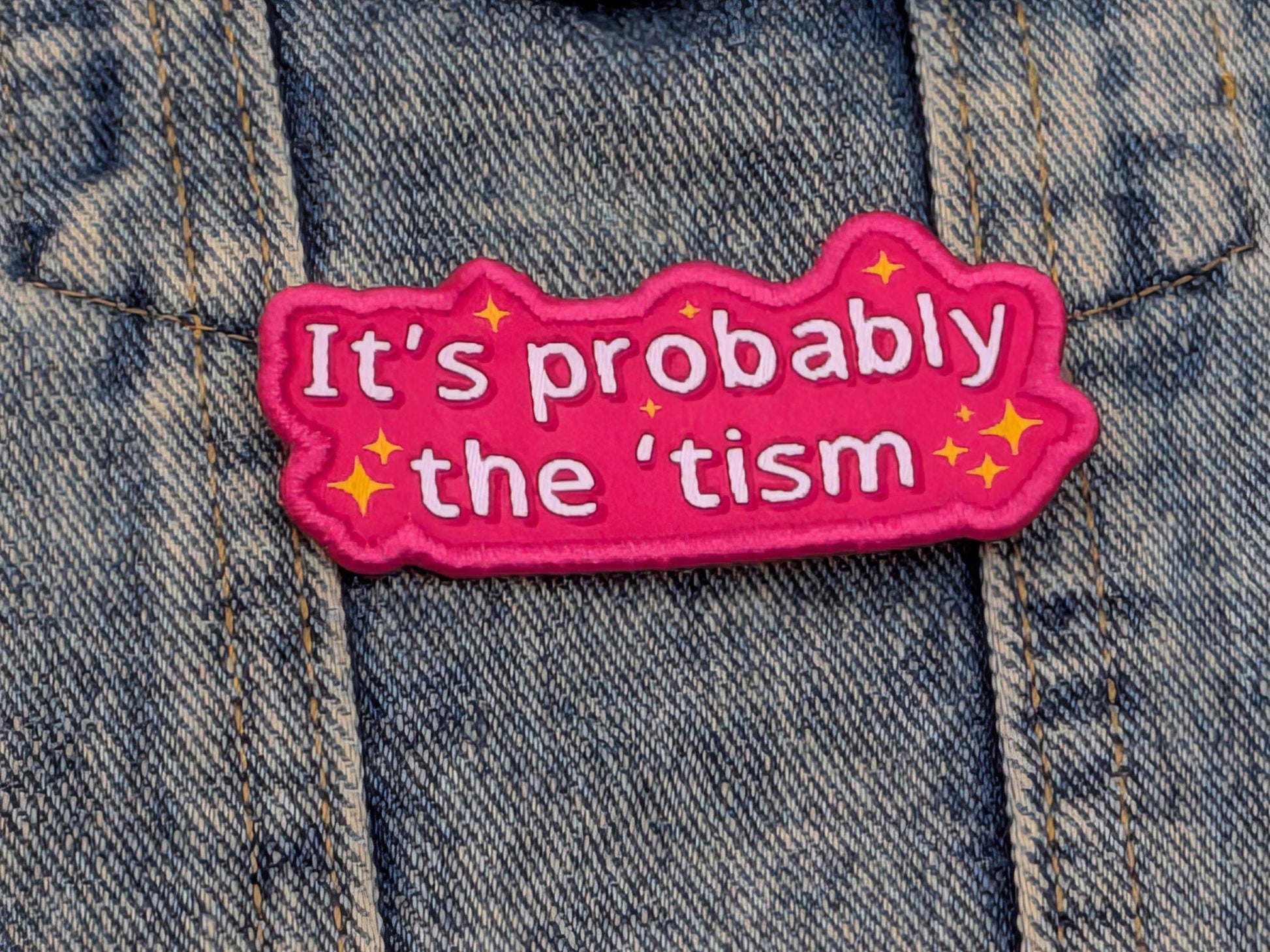 Pink patch with text 'It's probably the 'tism' on a denim background