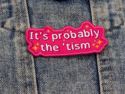 Pink patch with text 'It's probably the 'tism' on a denim background