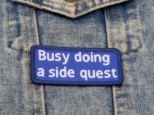 Patch on denim fabric with text 'Busy doing a side quest'