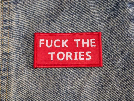 Red and white iron on patch with the words " fuck the tories" on a denim background