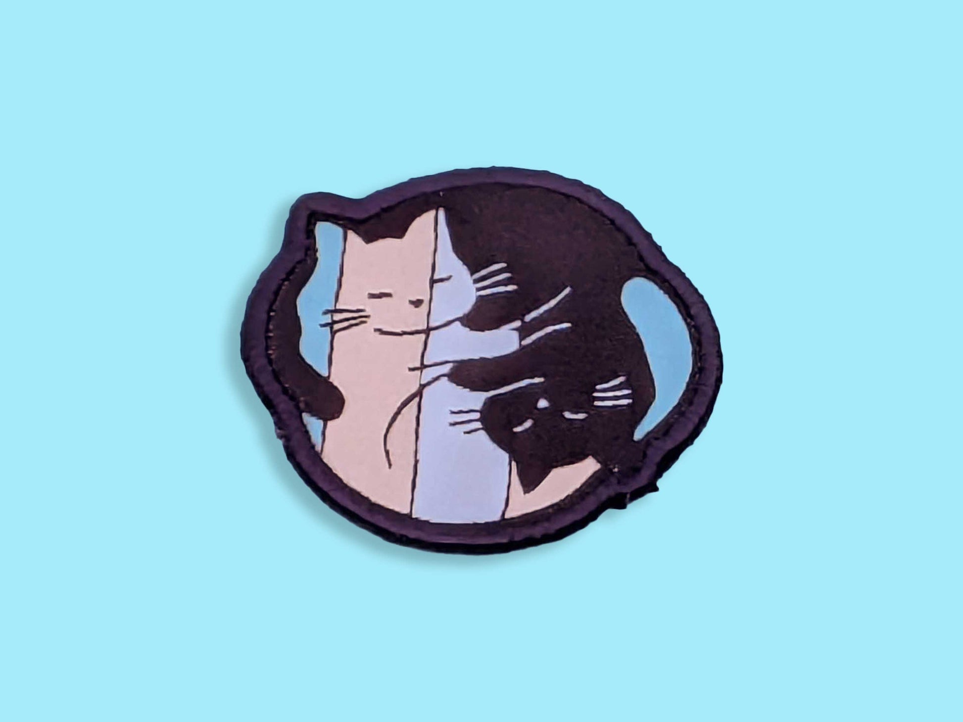 Patch with a ying yang style cat design in the trans flag colours