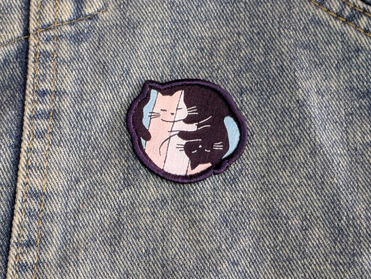 Embroidered patch of two cats on a denim background