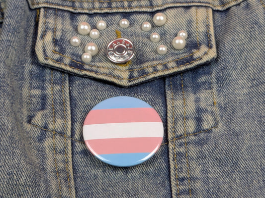 Transgender pride flag button on a denim jacket with pearl buttons.
